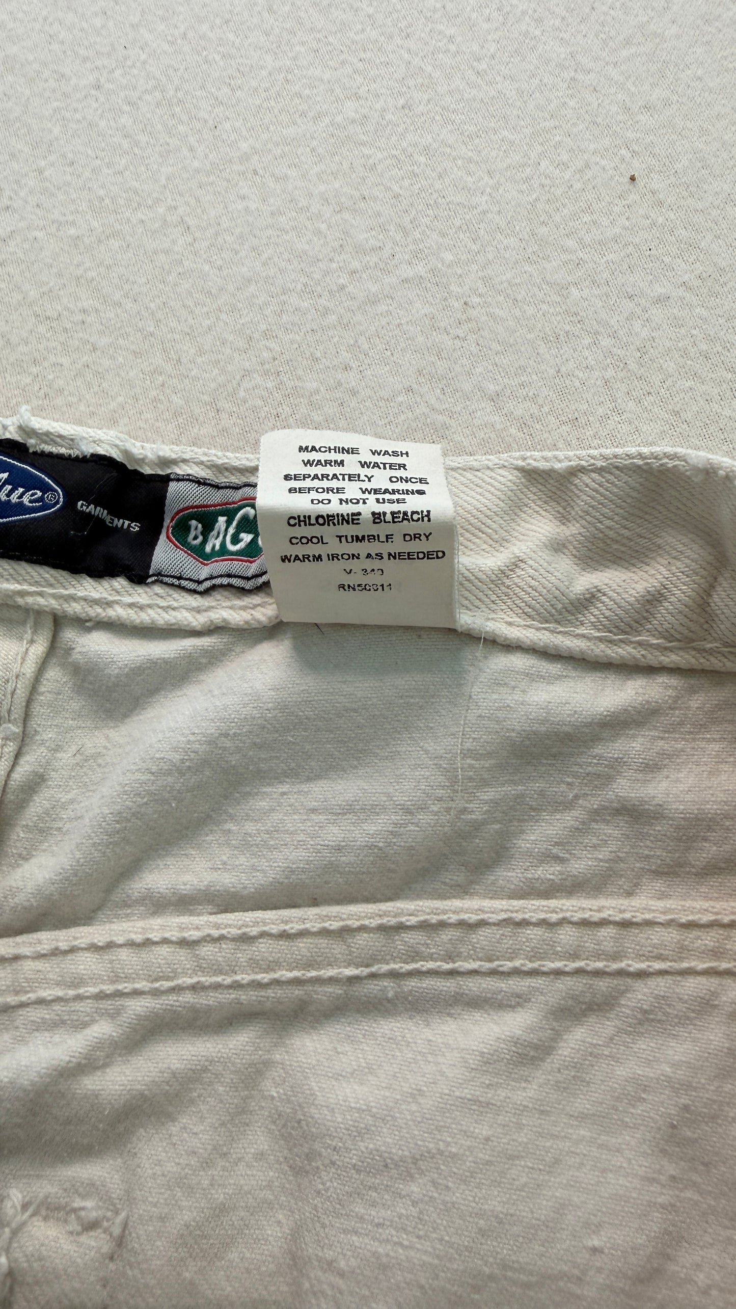 Close-up of a label on a pair of light-colored jeans with a visible brand logo.
