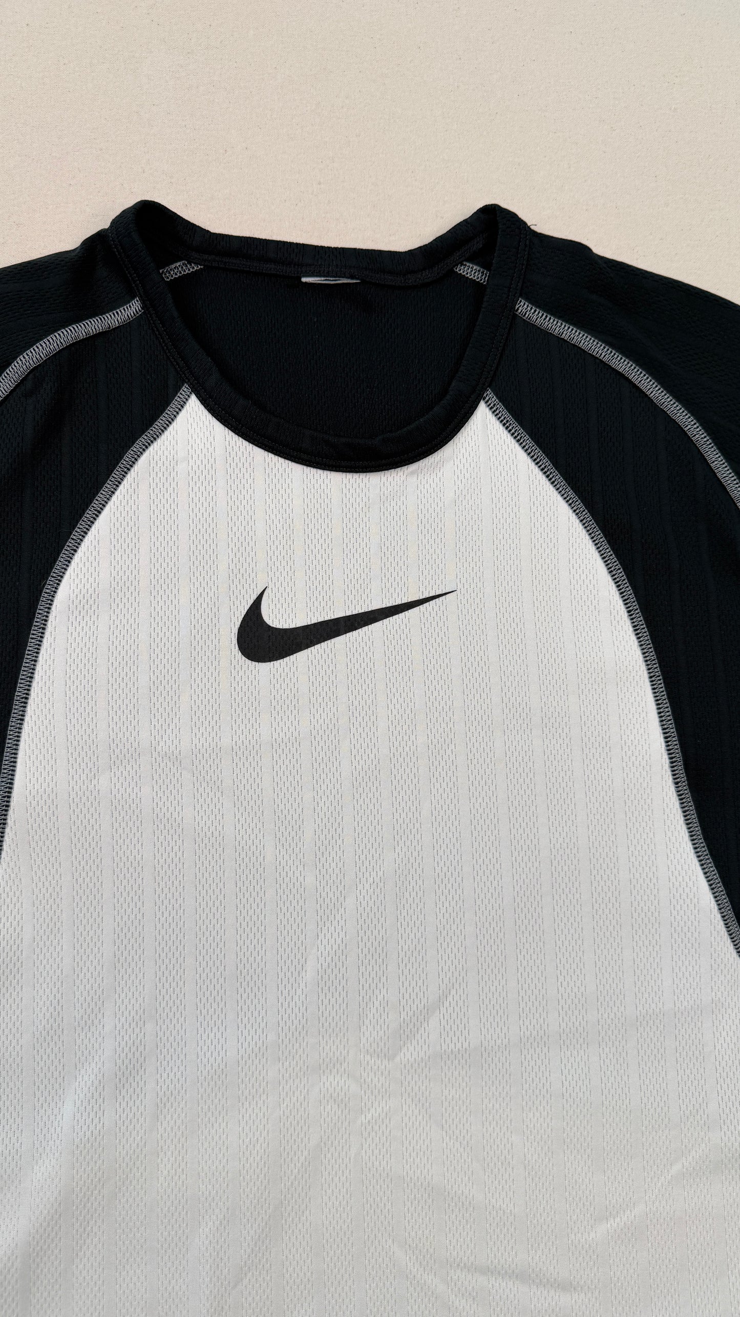 Black and white athletic shirt with Nike logo on a beige background