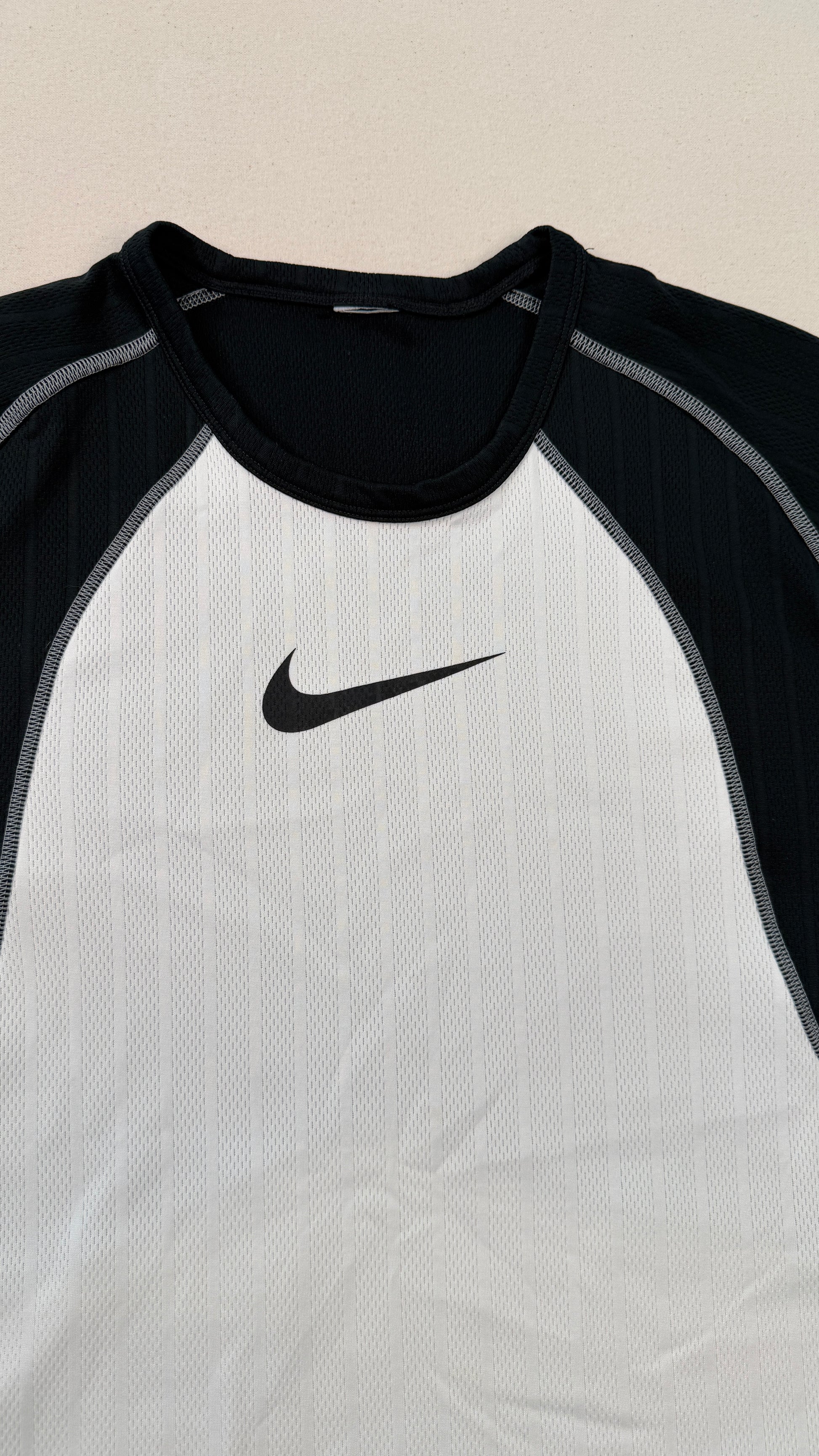 Black and white athletic shirt with Nike logo on a beige background