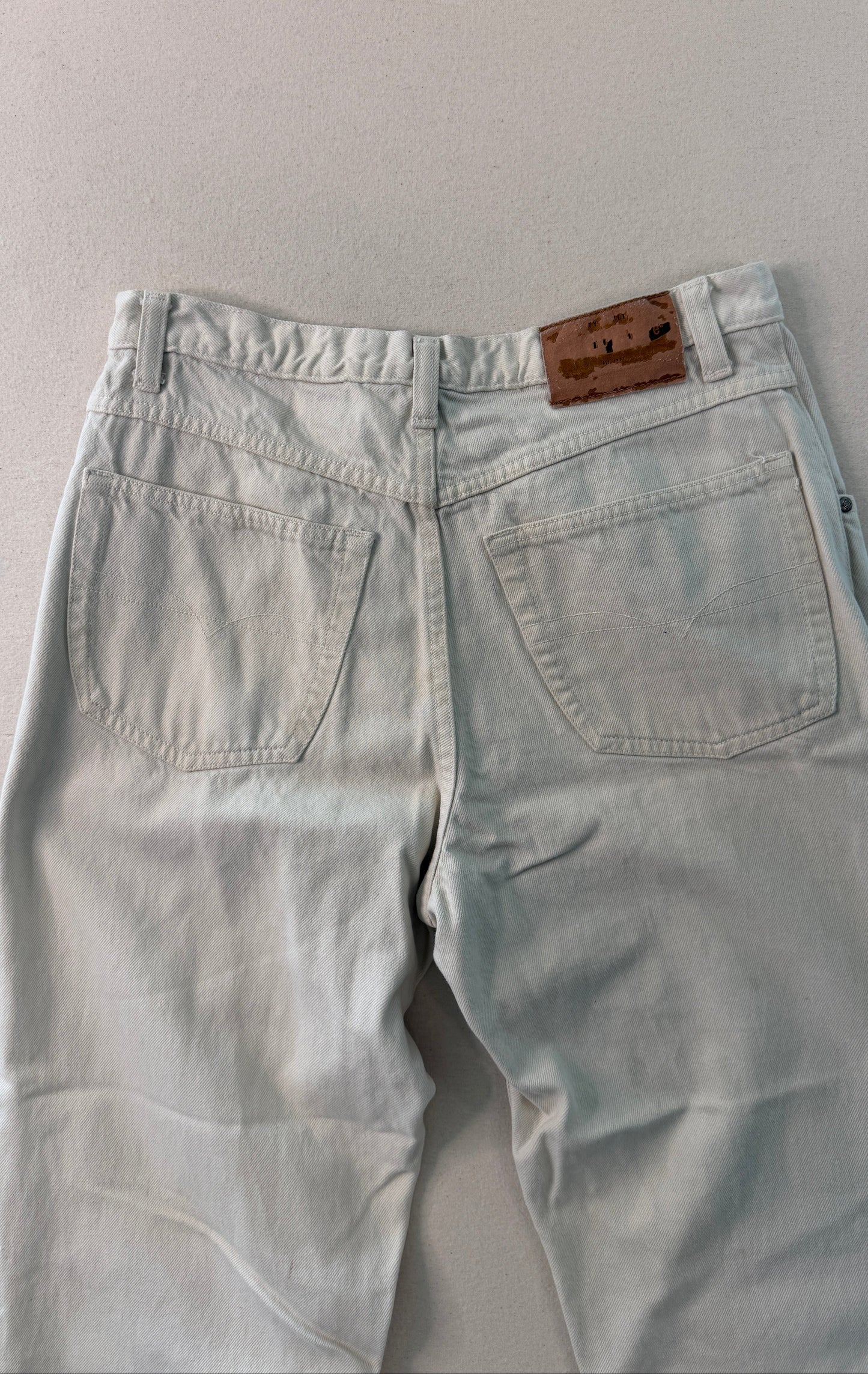 Light blue jeans with a brown leather patch on a gray background