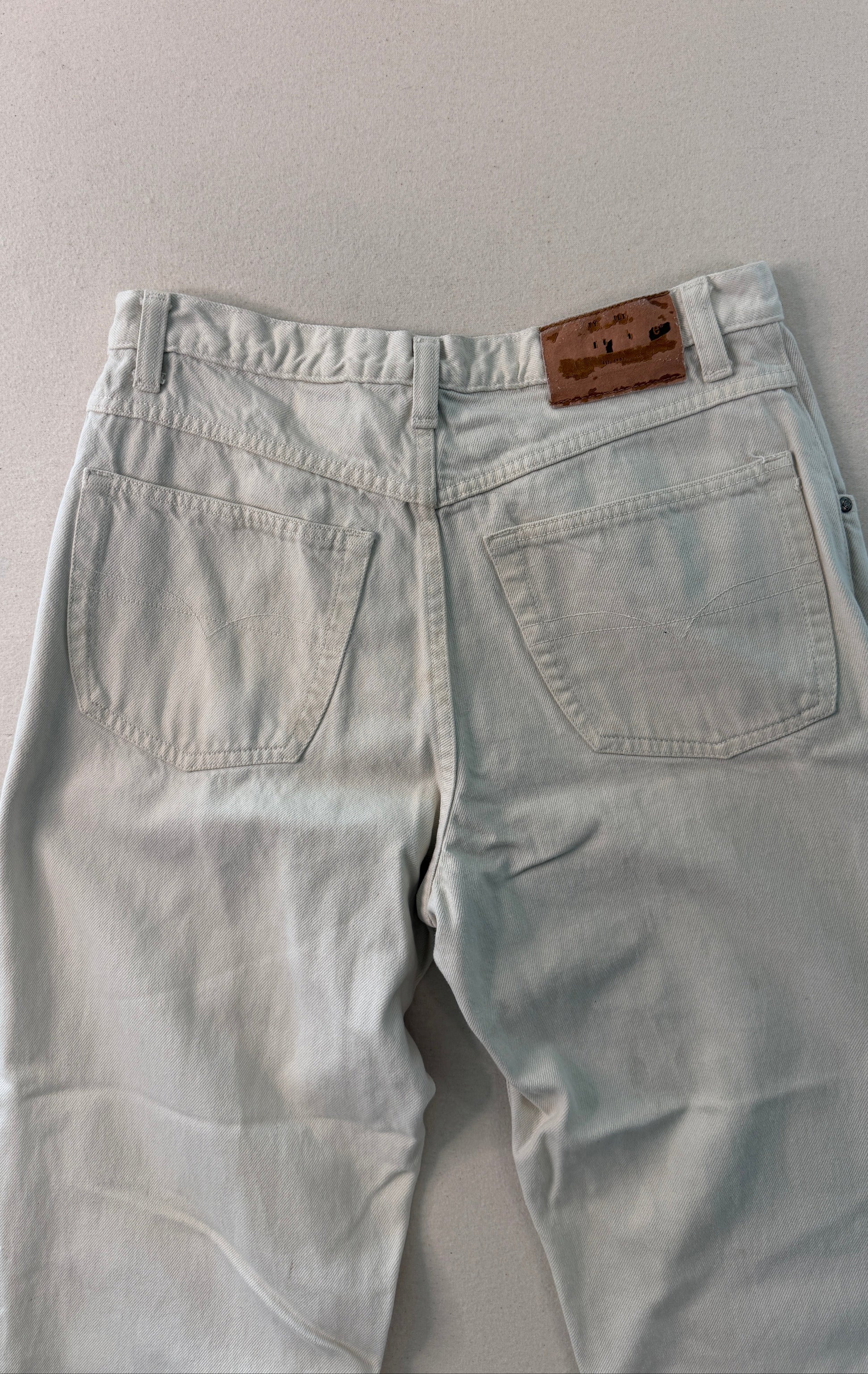 Light blue jeans with a brown leather patch on a gray background
