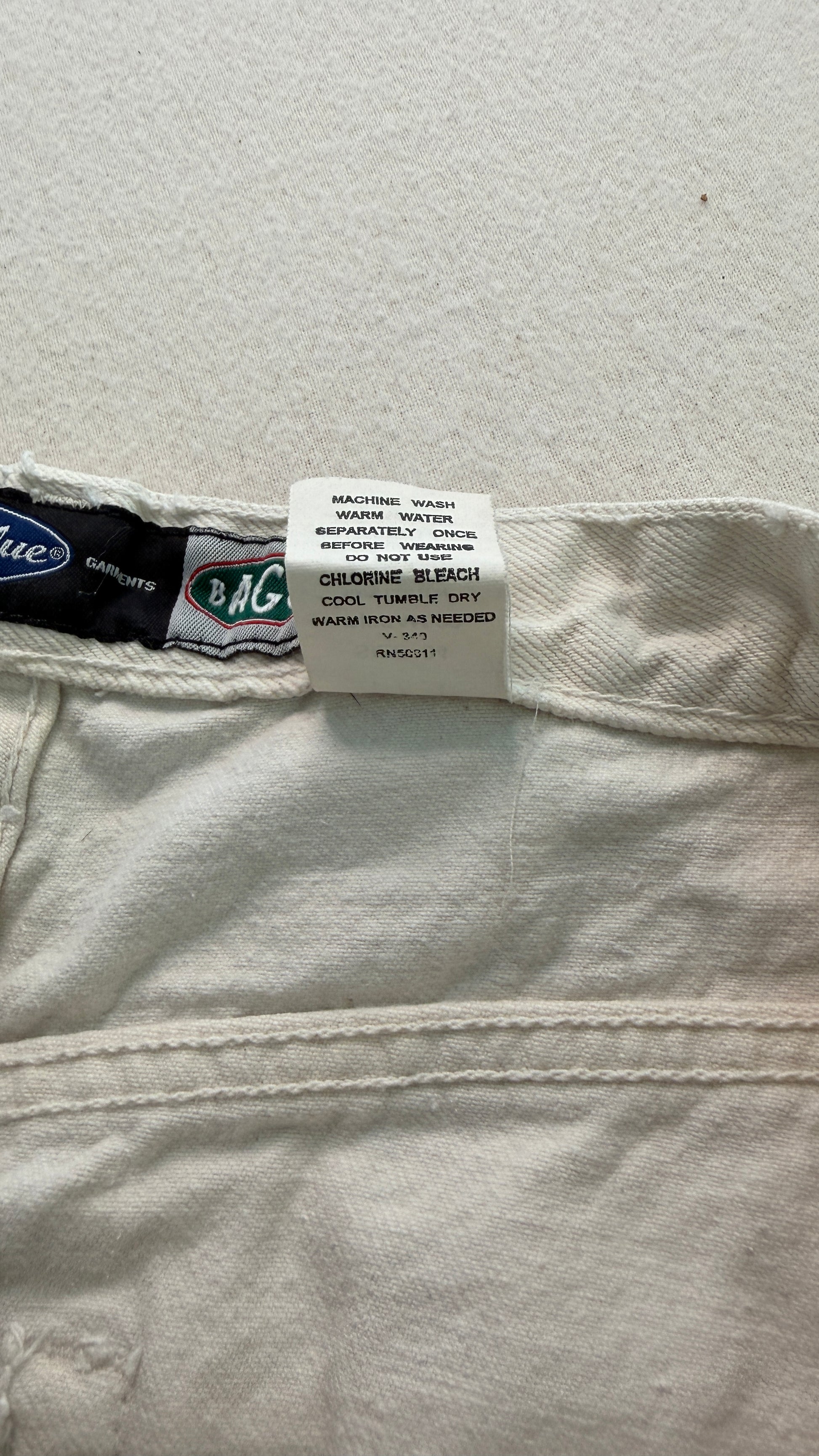 Close-up of a label on a pair of light-colored jeans with a visible brand logo.