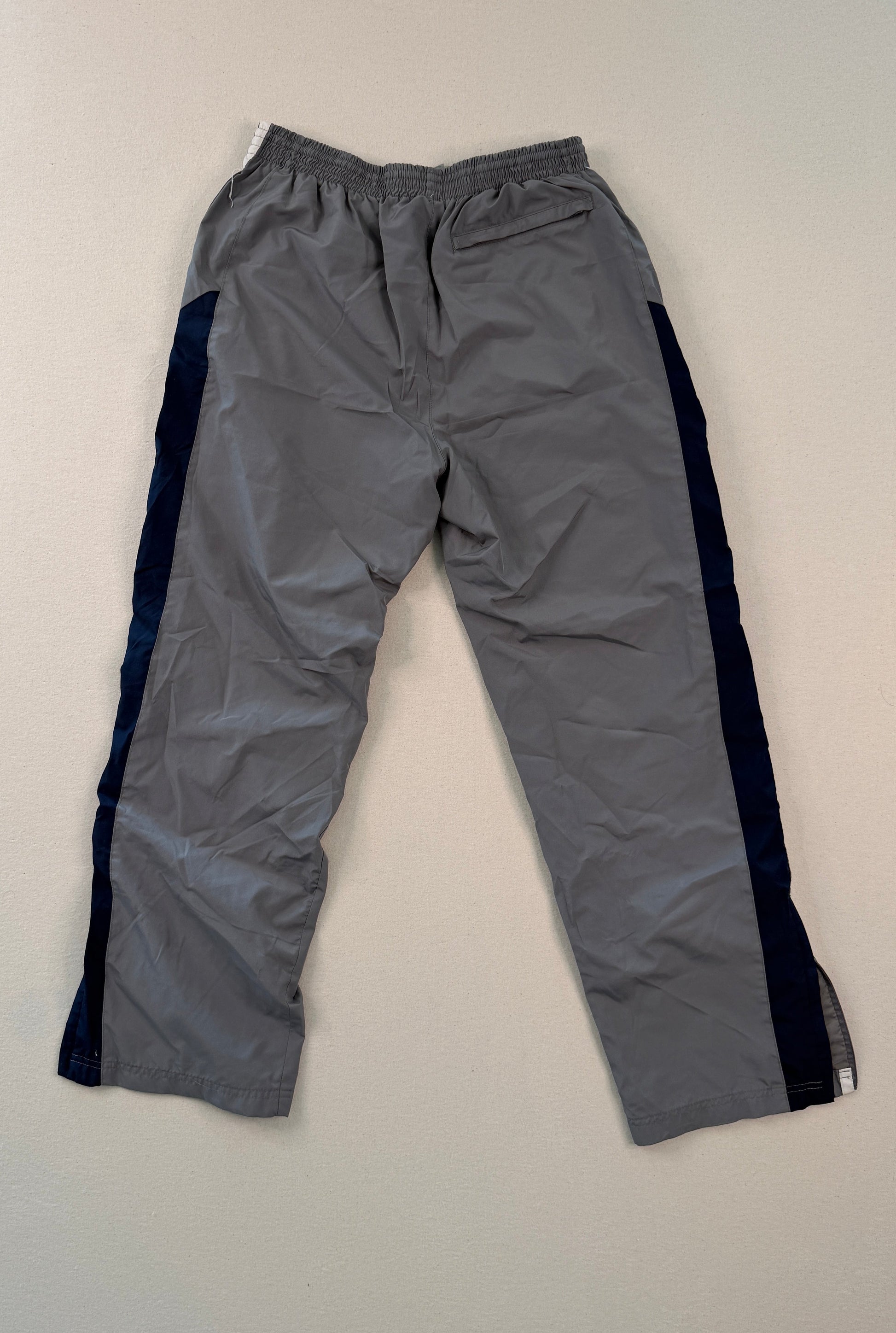 Gray pants with black side panels on a beige surface