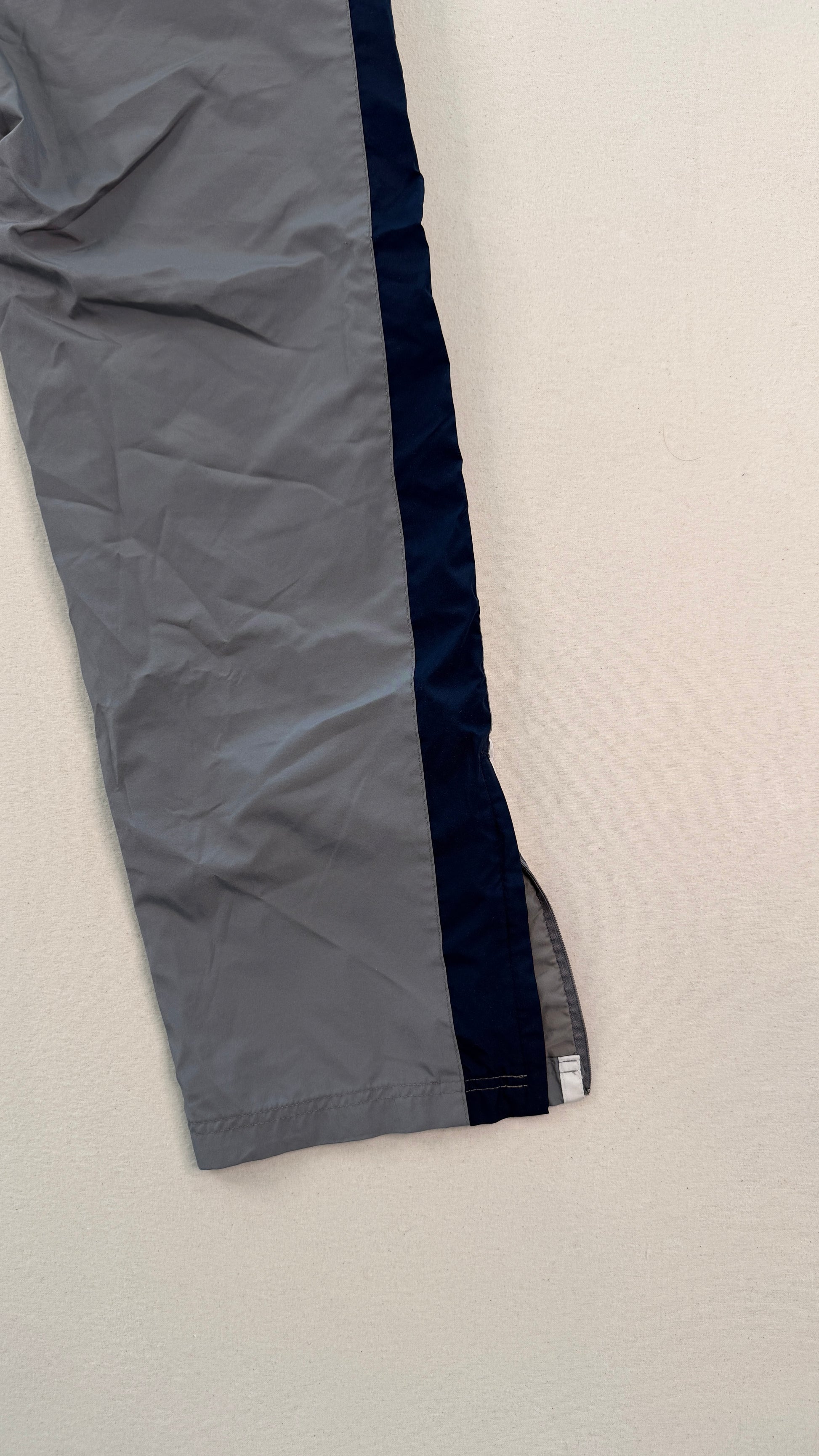 Close-up of gray pants with a visible brand label on a light beige background