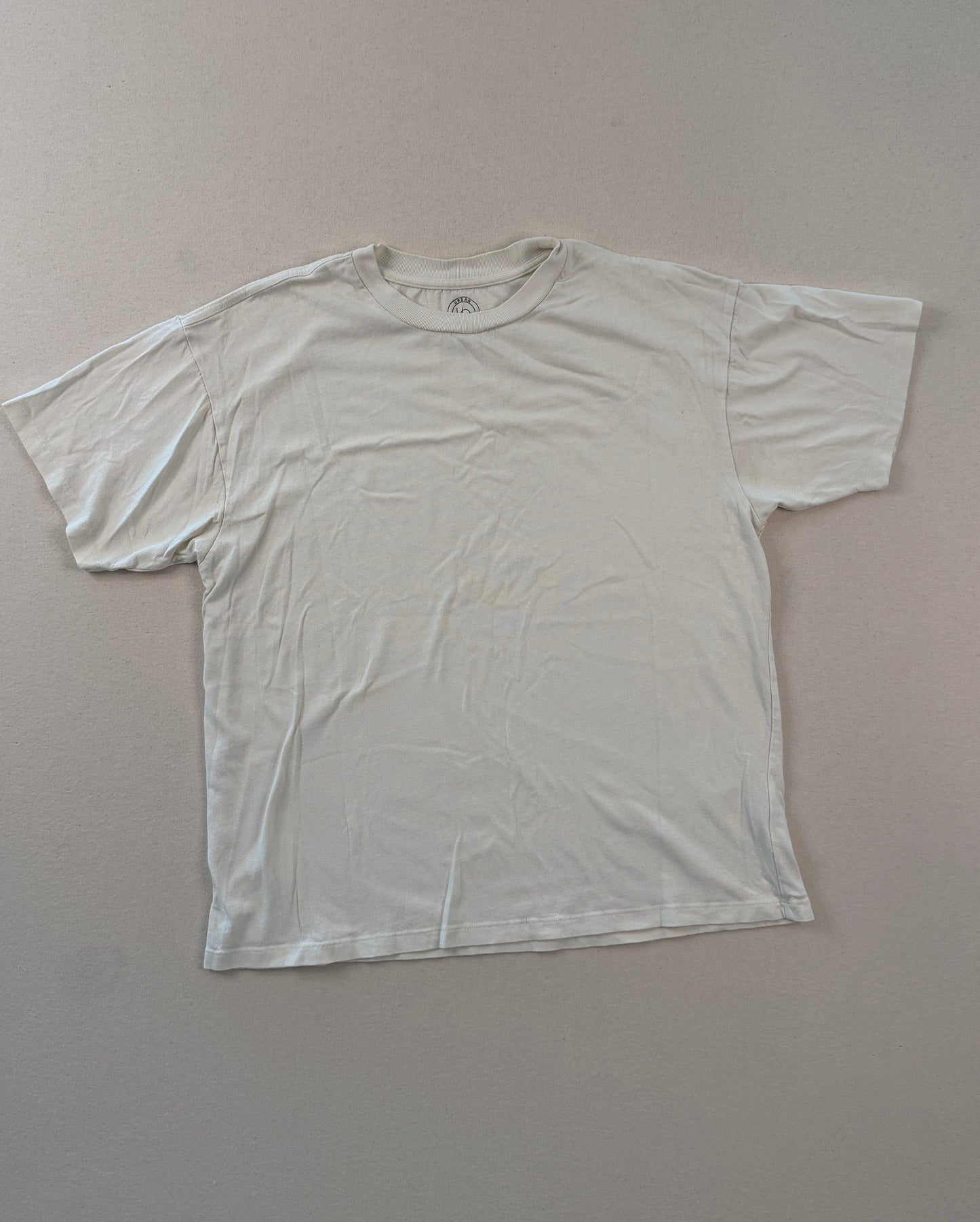 White t-shirt on a light gray surface with a ruler at the bottom.