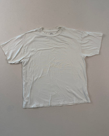 White t-shirt on a light gray surface with a ruler at the bottom.