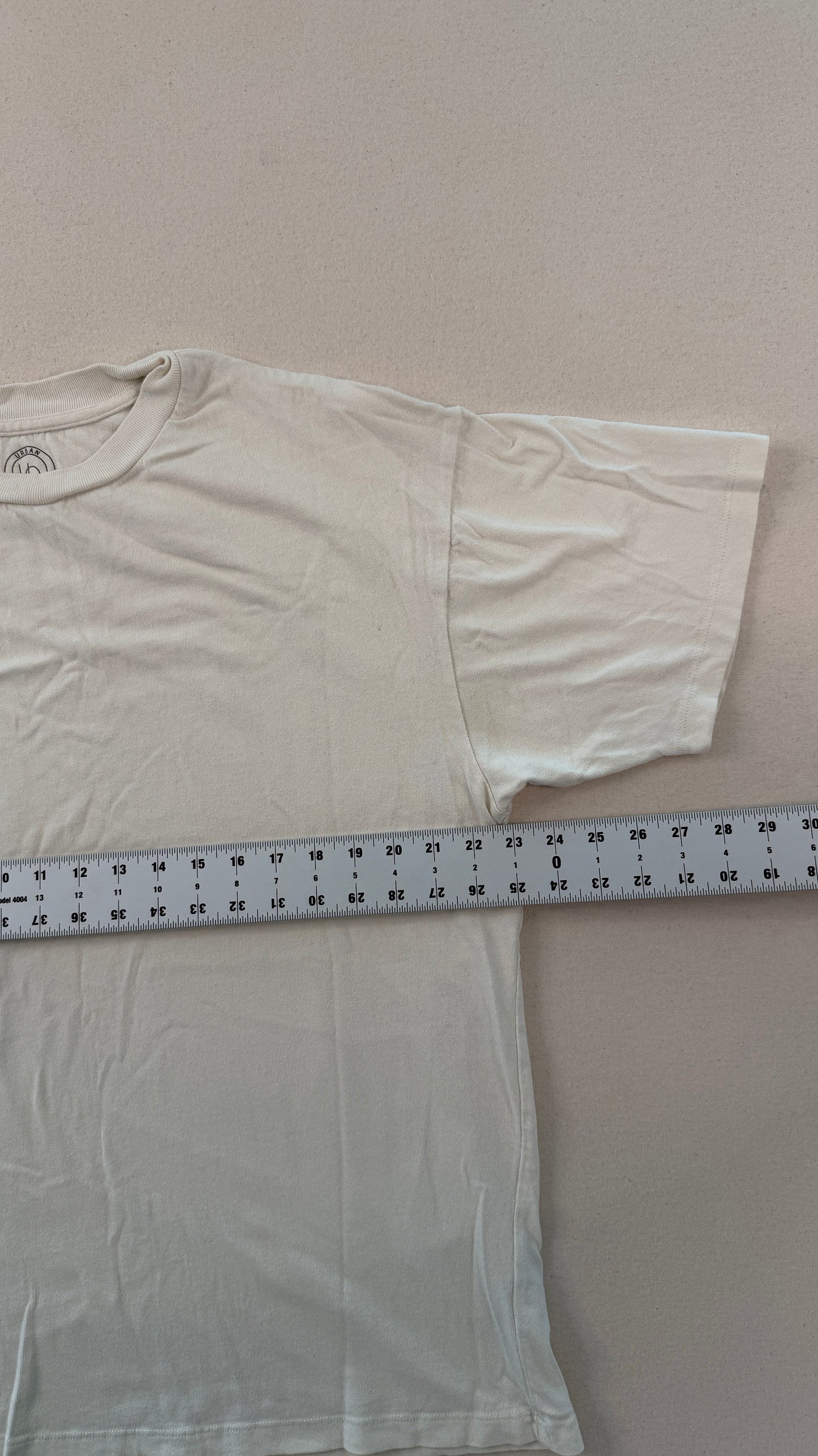 White t-shirt with a measuring tape laid across it on a plain background