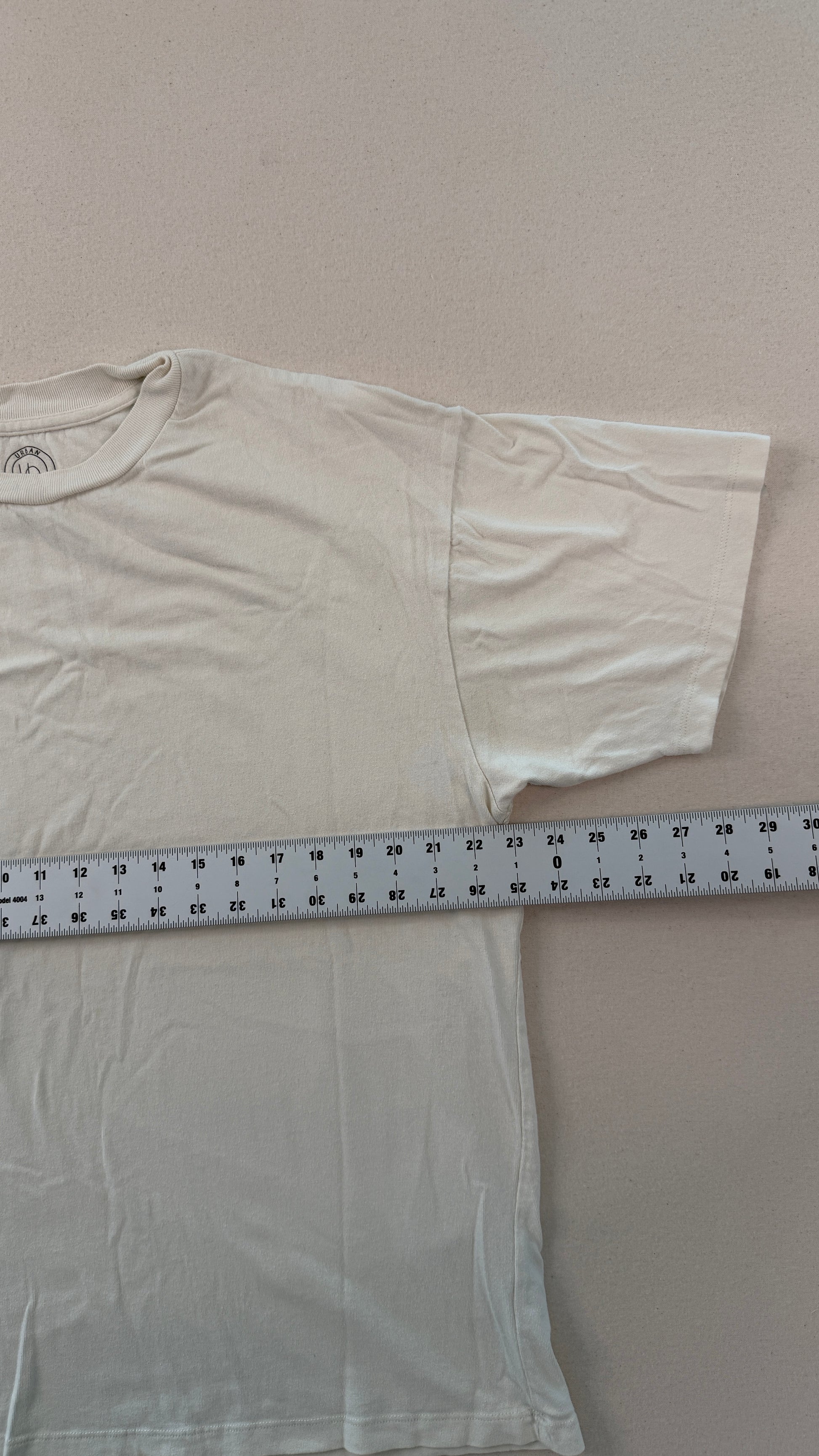 White t-shirt with a measuring tape laid across it on a plain background