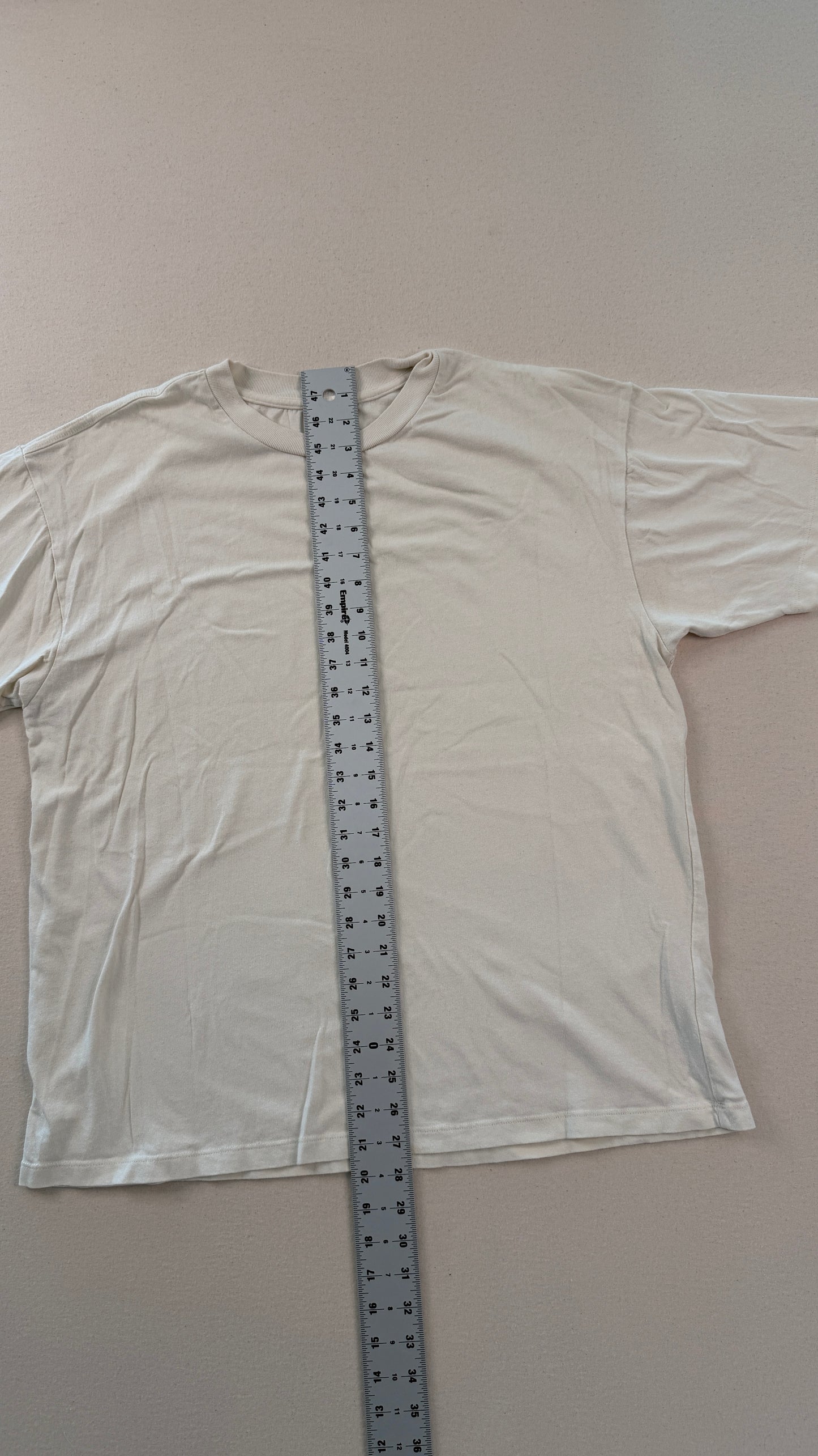 White t-shirt with a ruler for size reference on a plain background