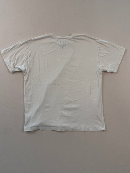 White t-shirt on a beige surface with a ruler at the bottom.