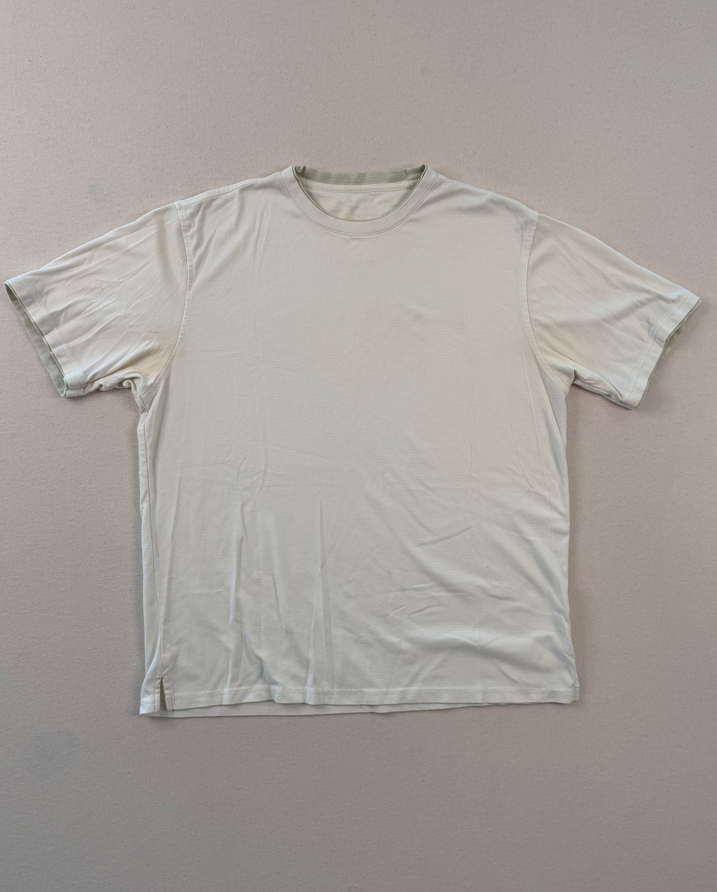 White t-shirt on a gray surface with a ruler at the bottom.