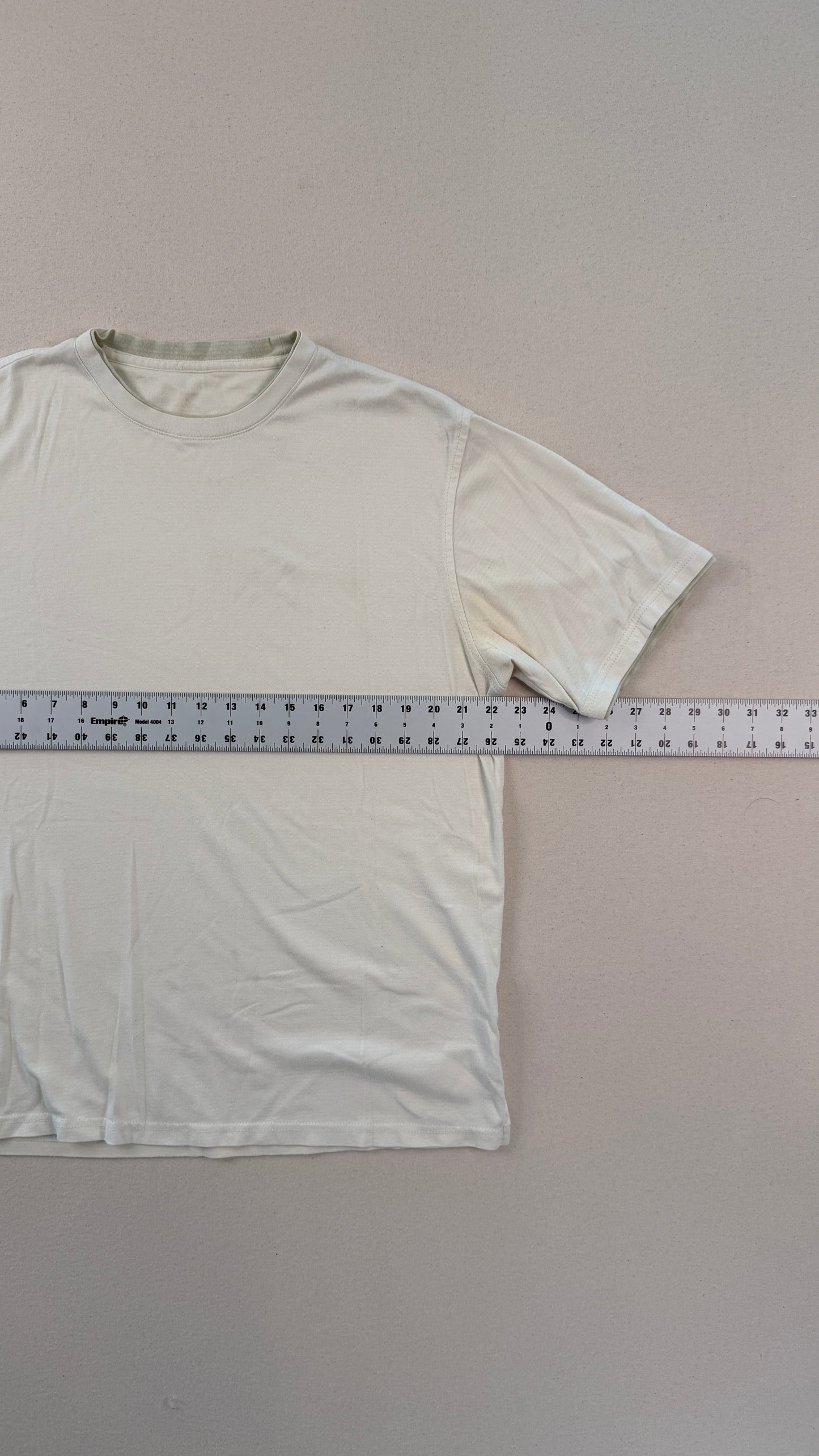 White t-shirt with a ruler for size reference on a gray background
