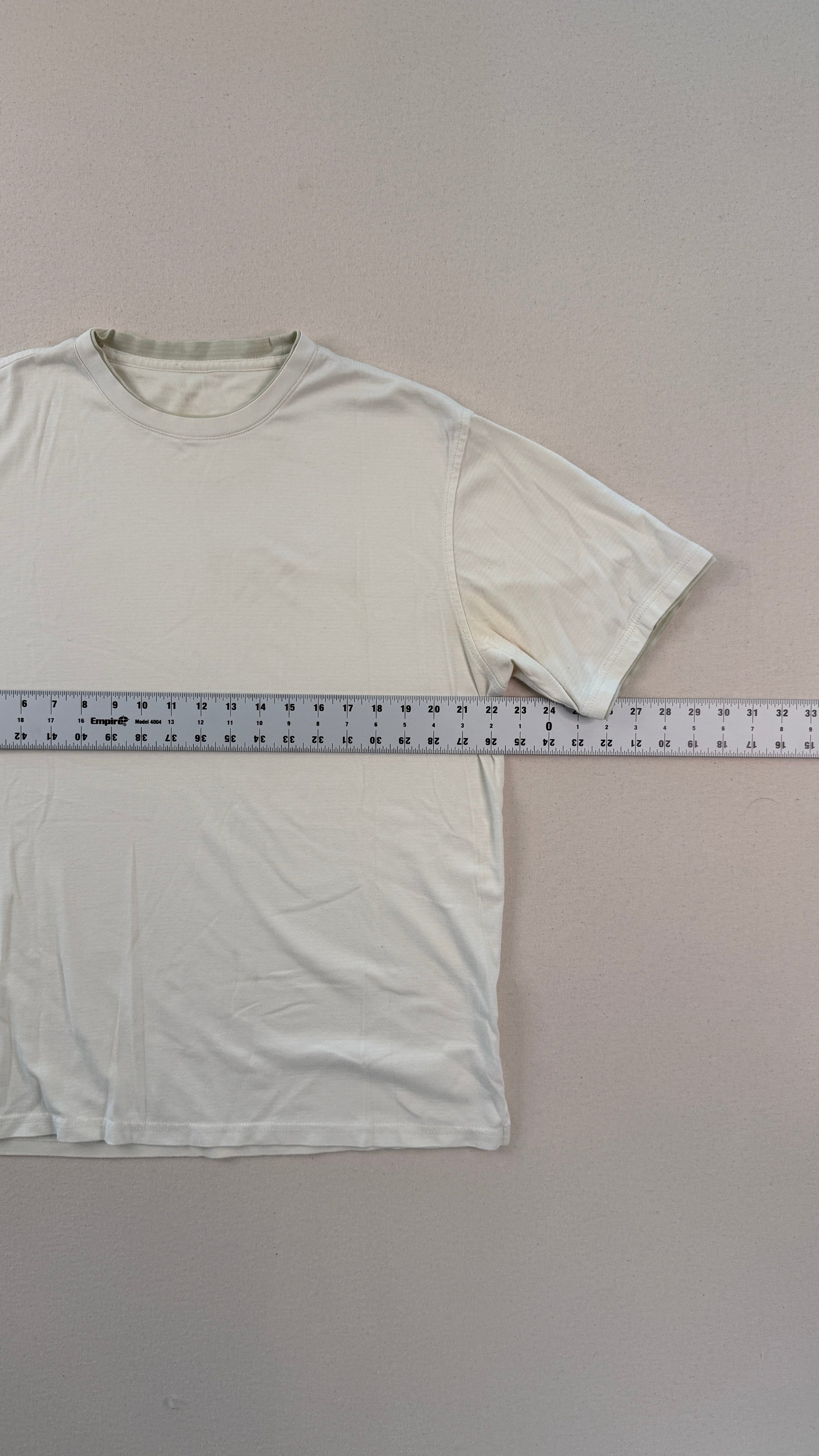 White t-shirt with a ruler for size reference on a gray background