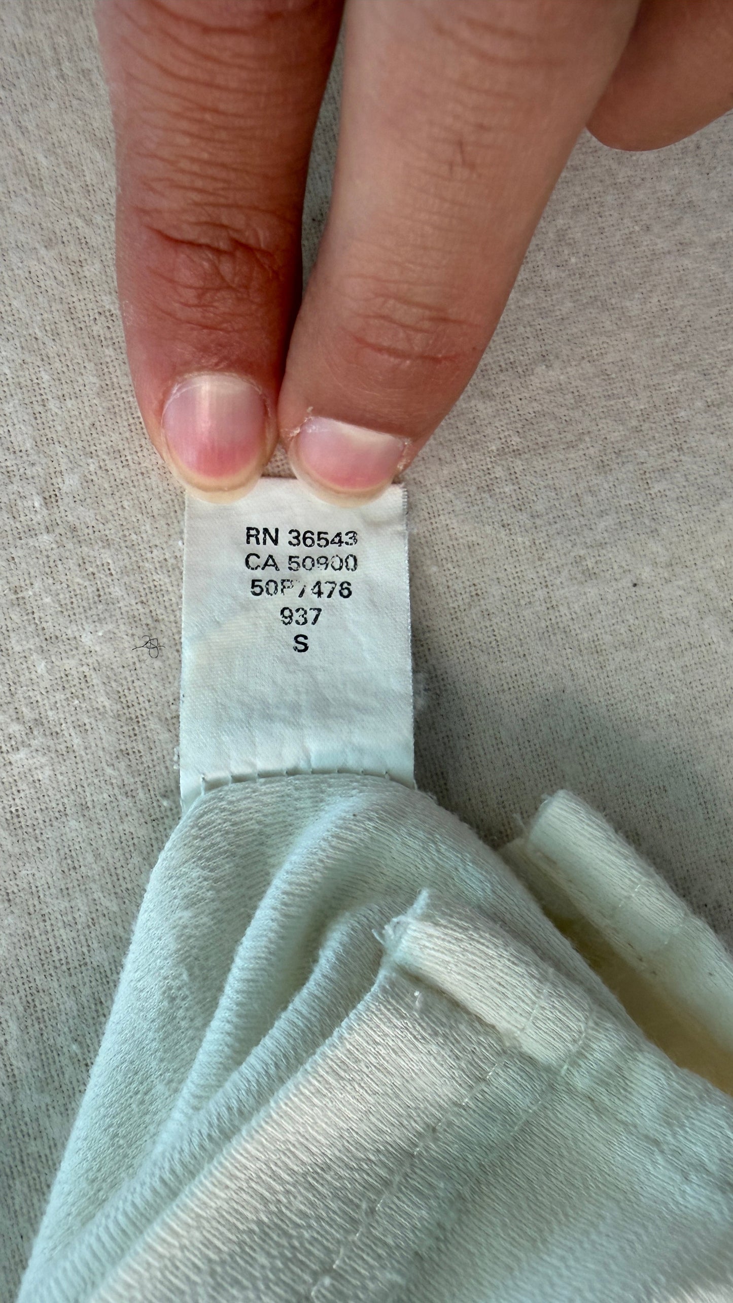 Light blue fabric with a tag held by a hand on a neutral background