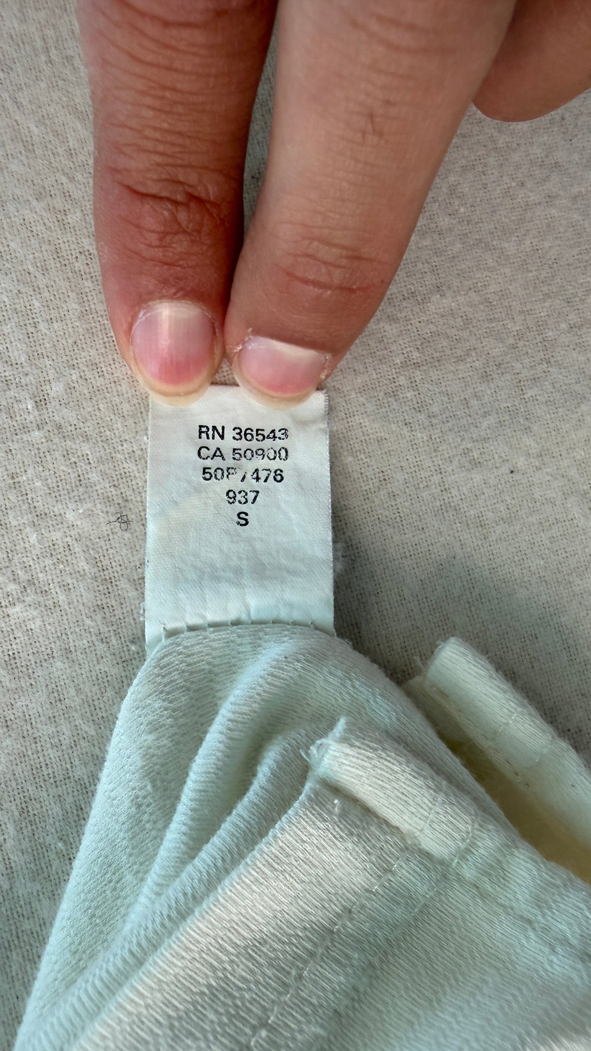 Light blue fabric with a tag held by a hand on a neutral background
