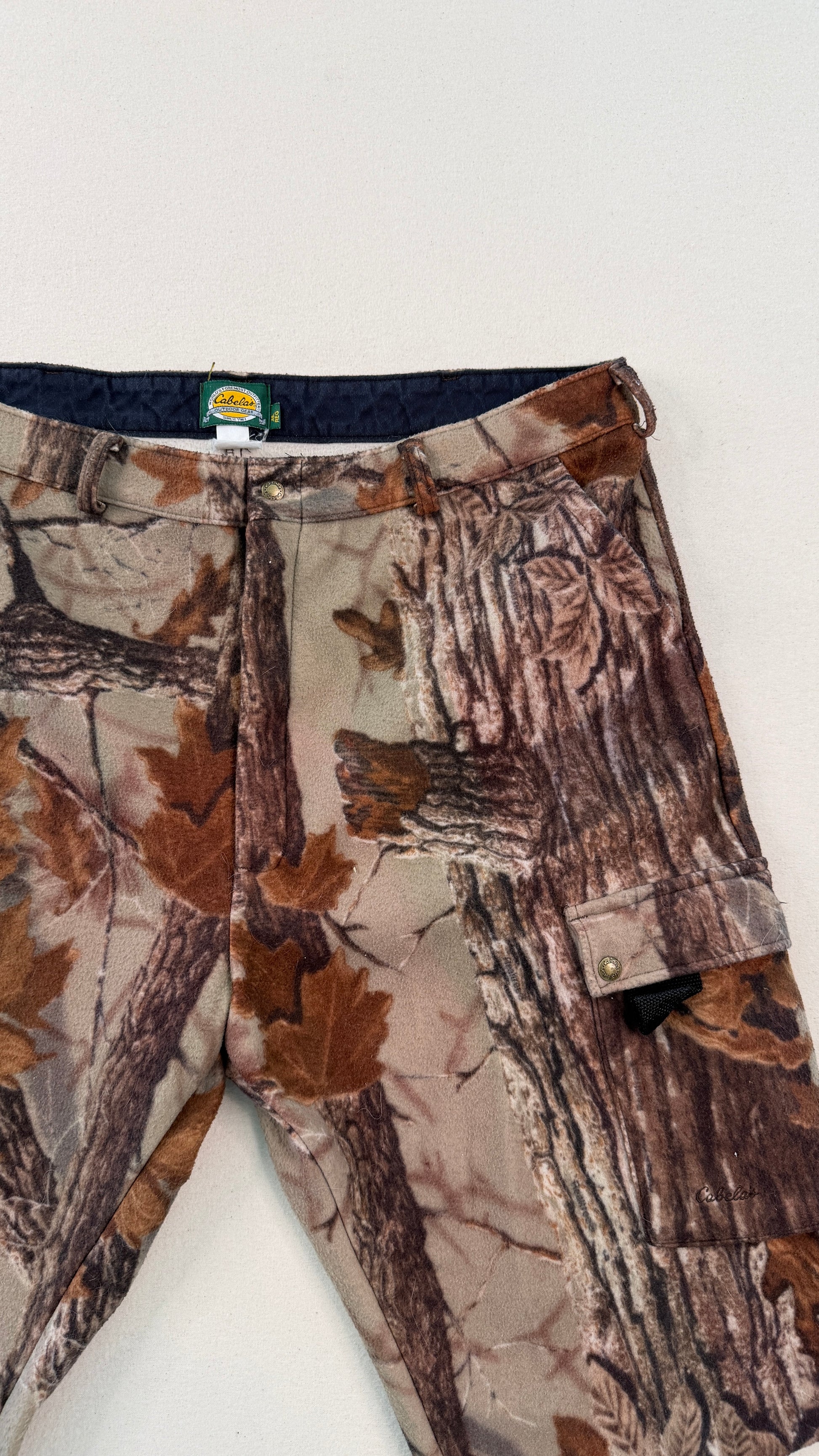 Camouflage pants with a visible brand tag on a white background
