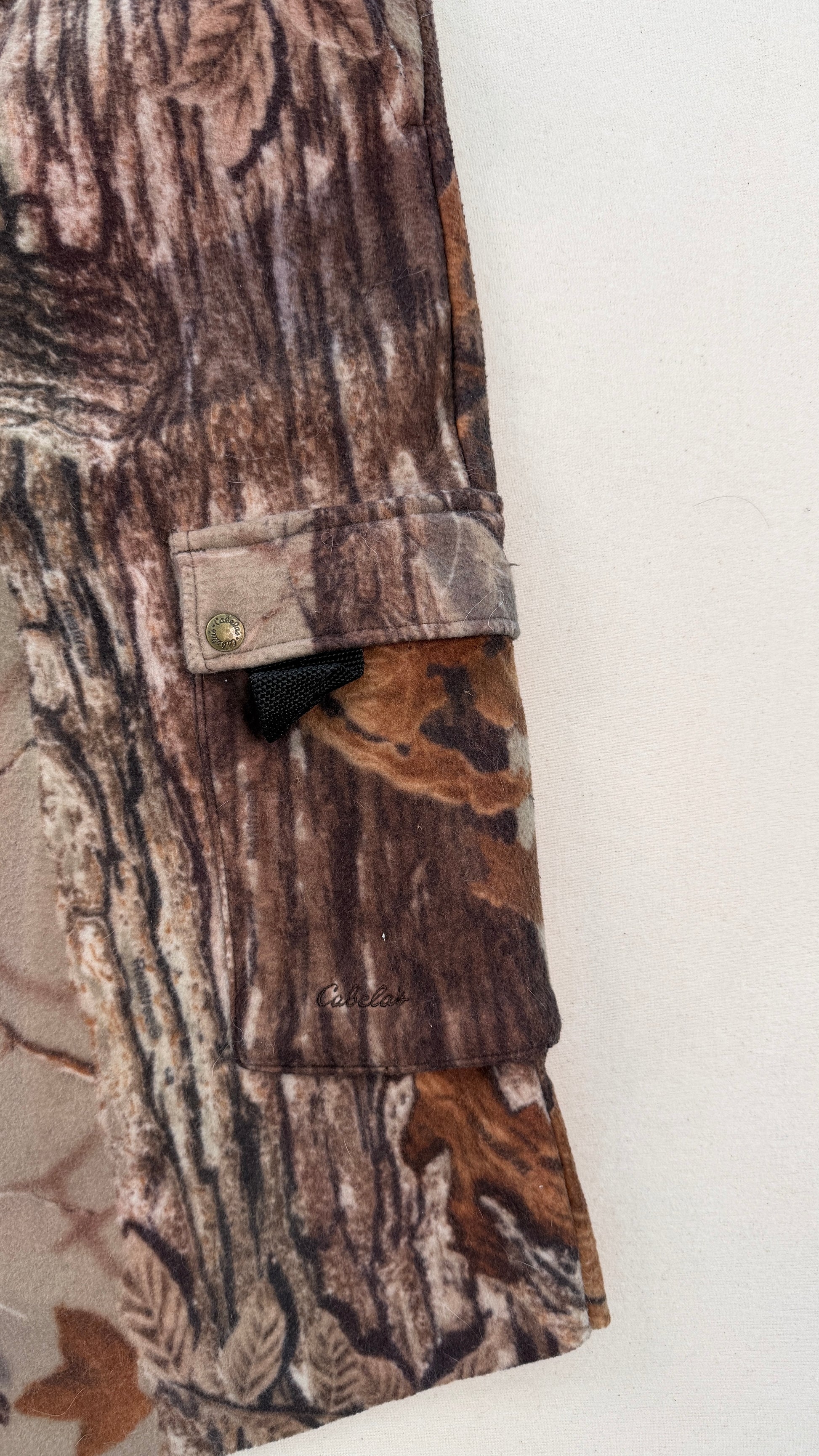 Close-up of camouflage pants with a button on a white background