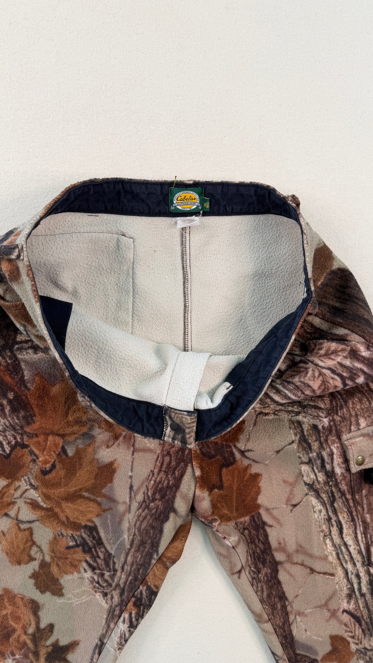 Close-up of a camouflage jacket with a visible brand logo on a white background