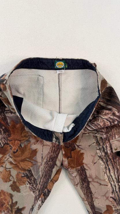 Close-up of a camouflage jacket with a visible brand logo on a white background