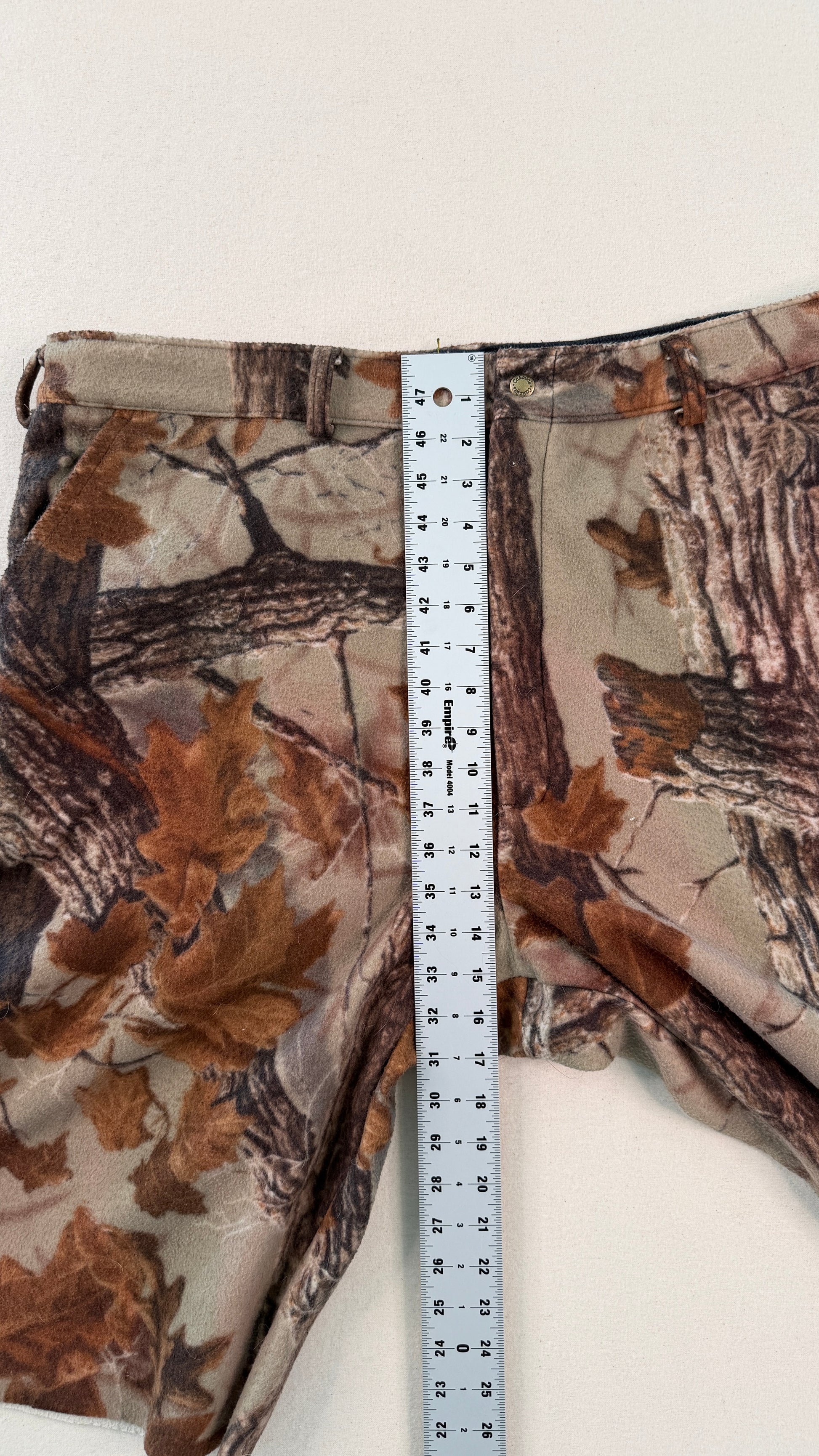 Camouflage pants with a measuring tape displayed on a white background