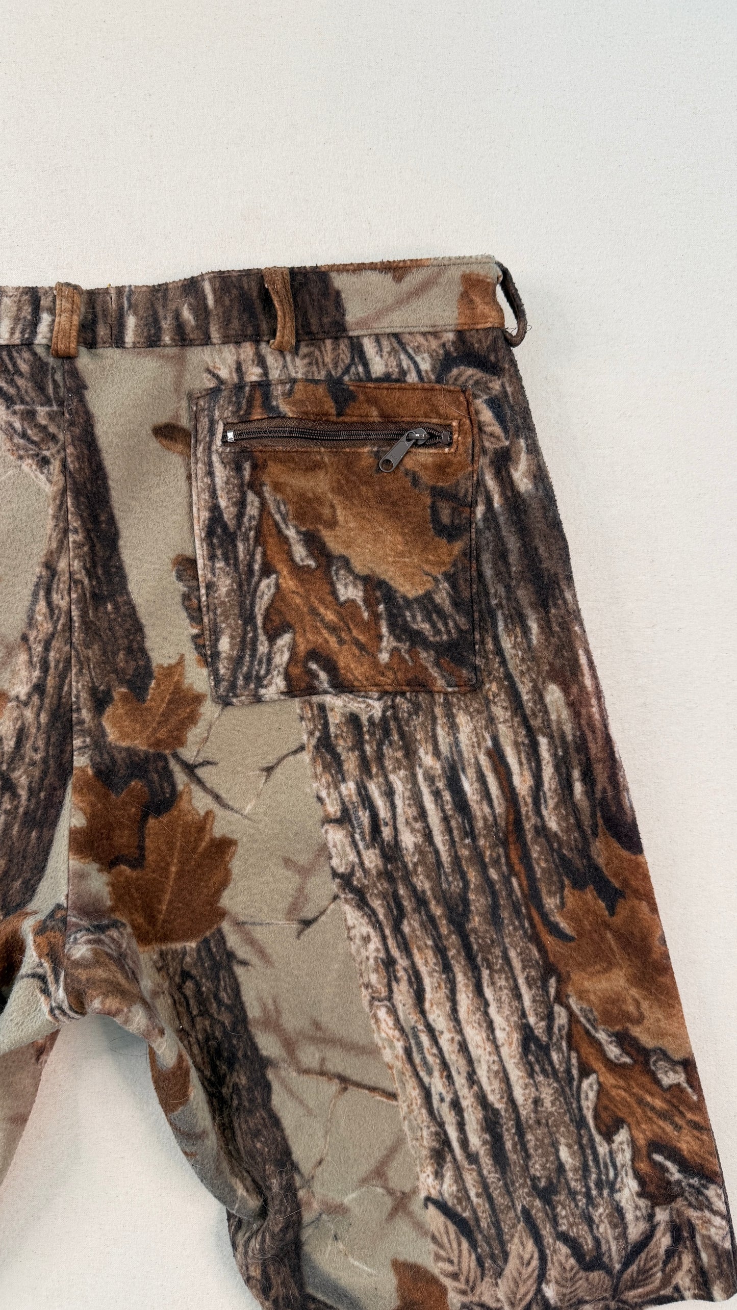 Camouflage pants with a pattern of brown, green, and beige on a white background