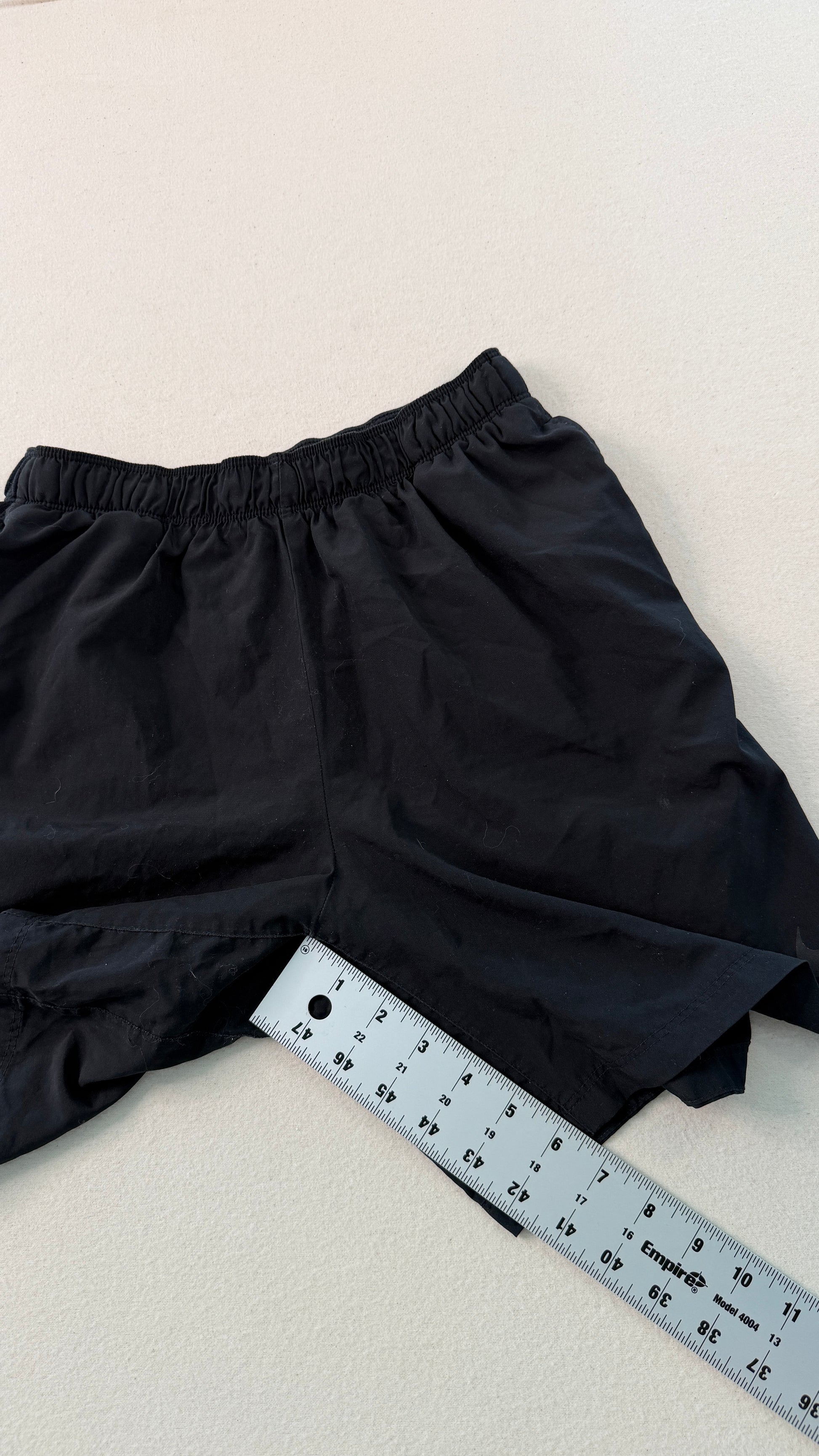 Black shorts with a ruler for size reference on a light background