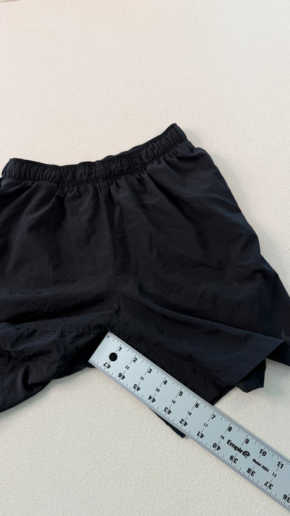 Black shorts with a ruler for size reference on a light background