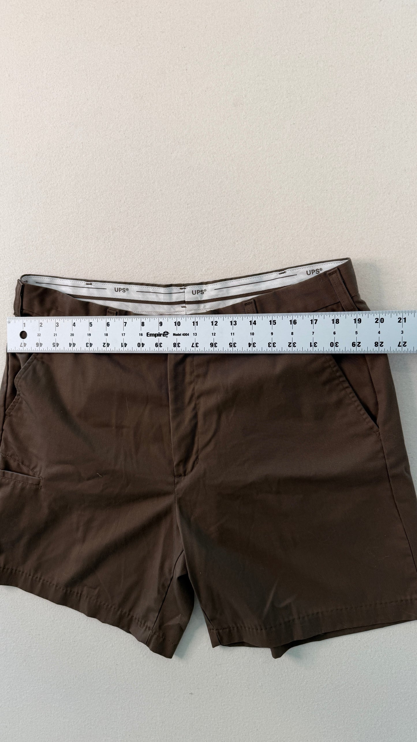Brown shorts with a ruler for size reference on a light background