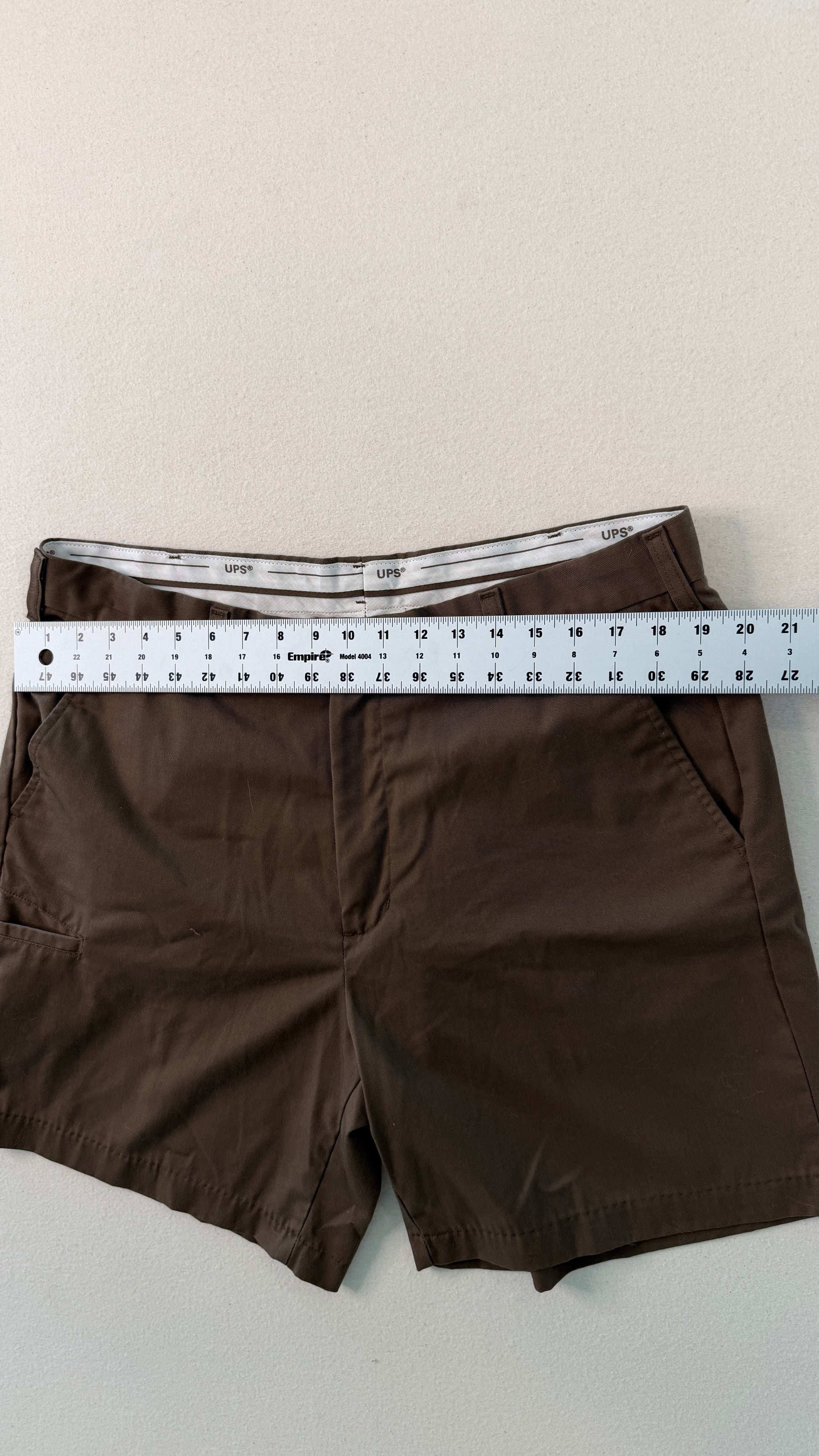 Brown shorts with a ruler for size reference on a light background