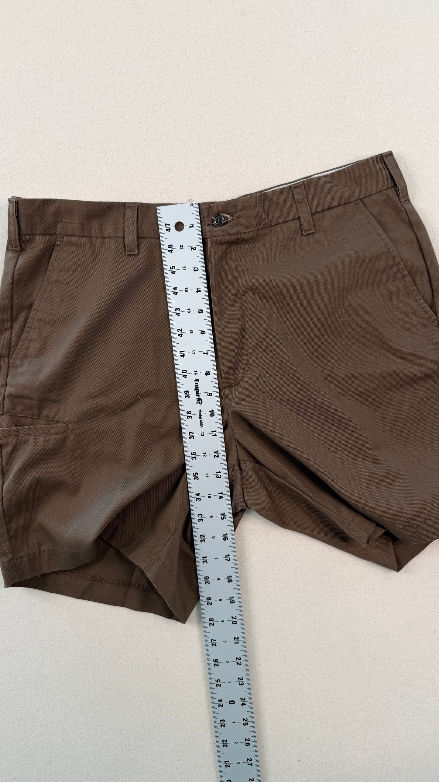 Brown shorts with a measuring tape across them on a light background