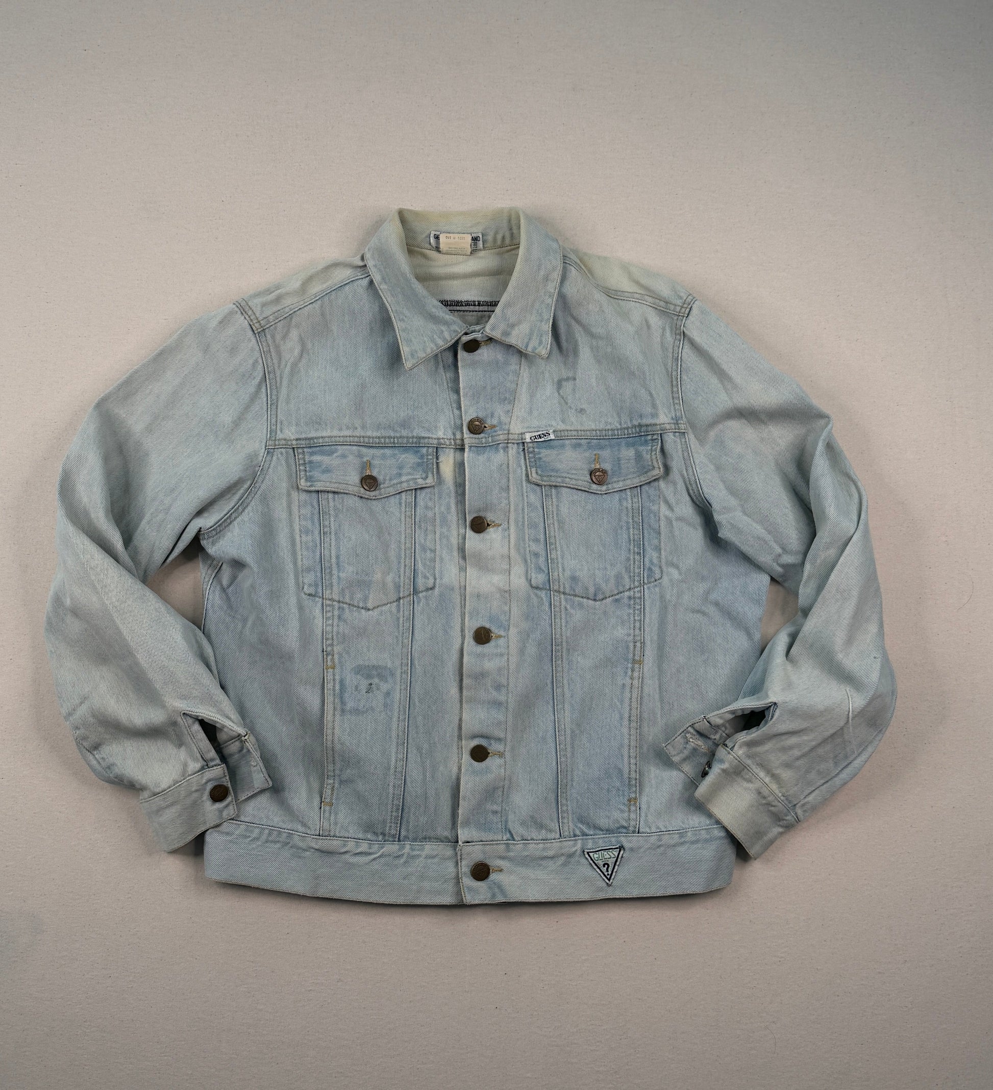Light blue denim jacket on a gray surface with a blurred window in the background