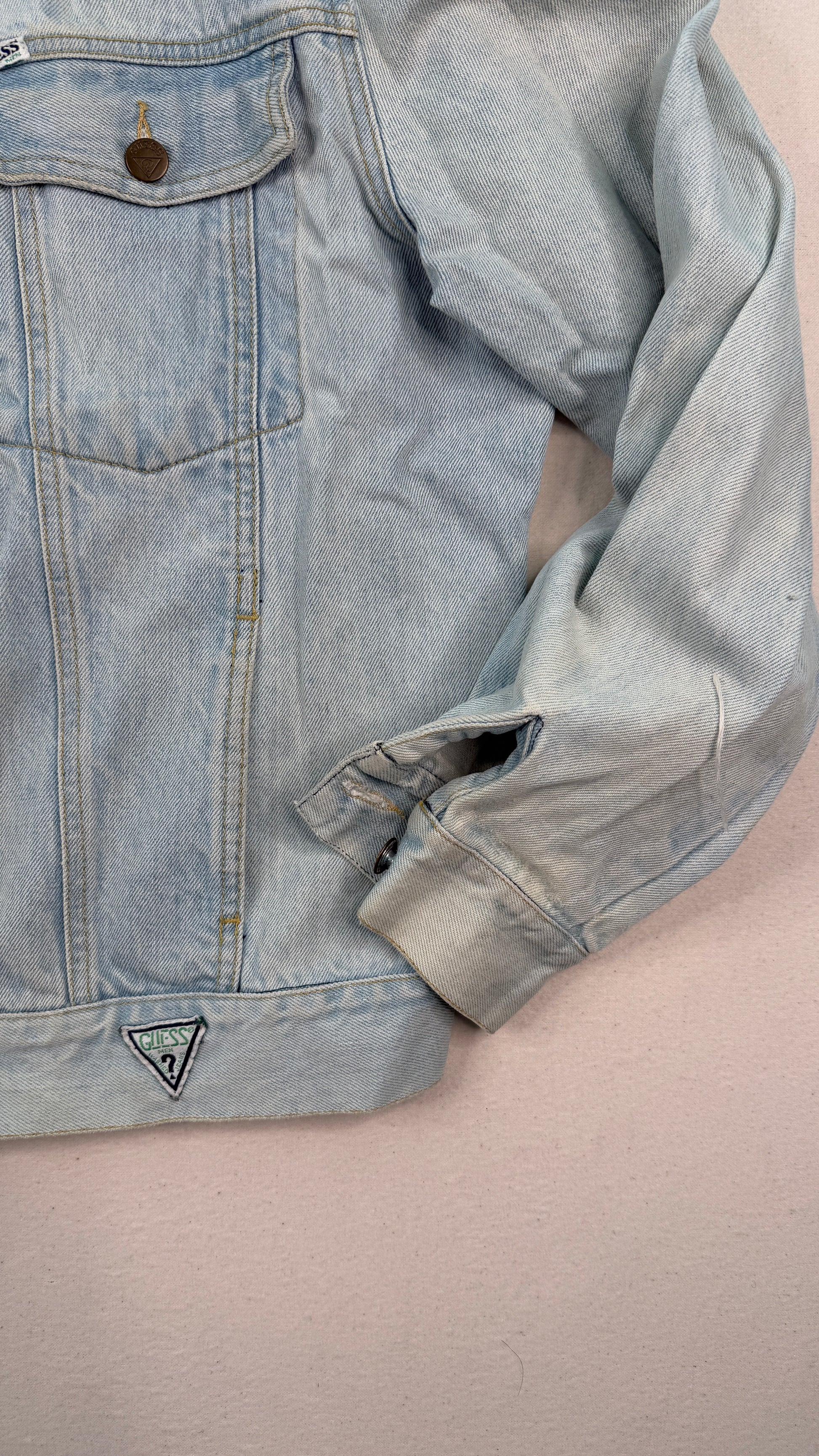 Light blue denim jacket with a brand logo on a beige background