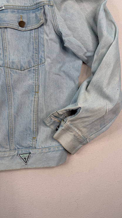 Light blue denim jacket with a brand logo on a beige background