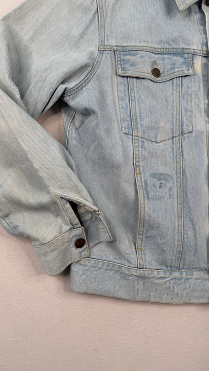Close-up of a light blue denim jacket on a beige surface